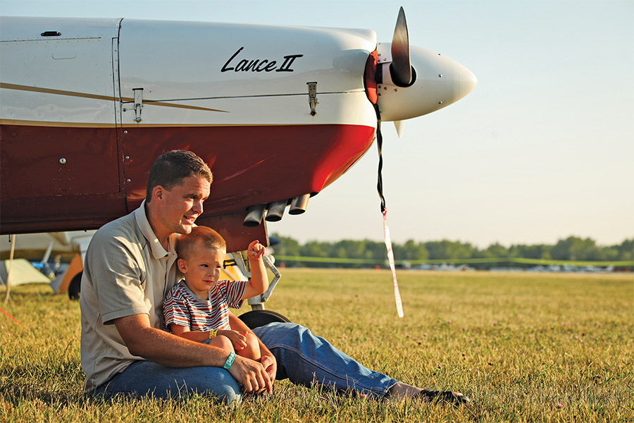 father and son sitting by airplane on north 40 at airventure oshkosh