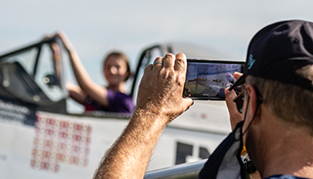 Airventure attendee taking picture of girl in plane