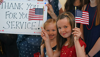 young girl holding flags for returning veterans on Old Glory Honor Flight in 2019