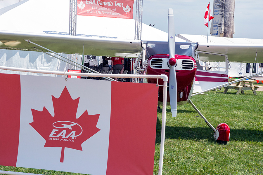 red plane positioned behind EAA Canada flag at AirVenture